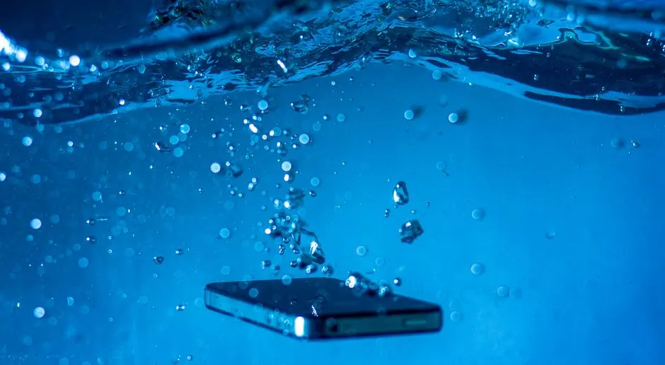 A smartphone submerged in water with bubbles rising around it, showcasing a dynamic underwater scene.